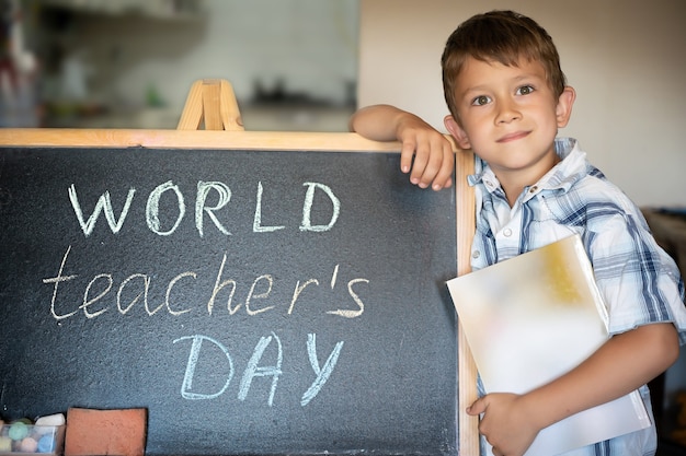 World Teacher's Day greeting, pupil boy near the chalkboard, chalk inscription text