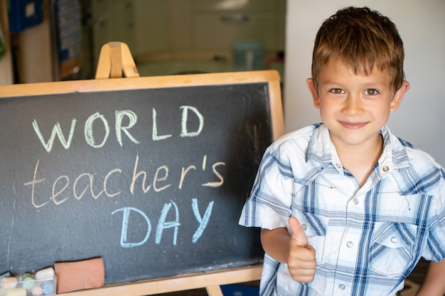 World Teacher's Day greeting, pupil boy near the chalkboard, chalk inscription text