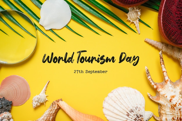 World Tourism Day incription over yellow background, with palm leaves, clam shell, and shoes flat lay background