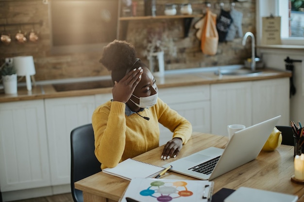 Worried African American businesswoman working on laptop at home dur to coronavirus pandemic