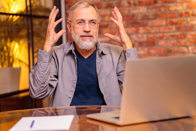 Worried aged man sit by laptop and try do make payment online