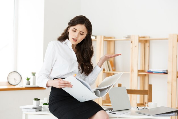 Worried businesswoman reading a notification report while is working sitting in a desk at office.