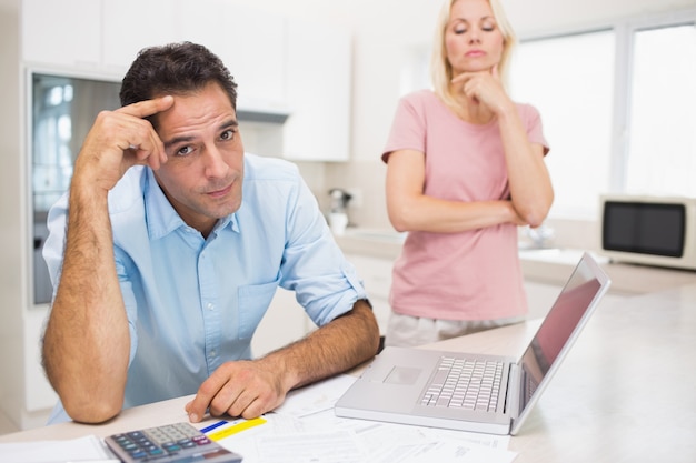 Worried couple with bills and laptop in kitchen