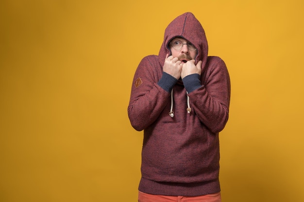 Worried frightened man hides while wearing the hood of his sweatshirt and looks anxiously