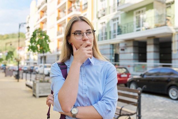 Worried insecure serious young business woman on city street