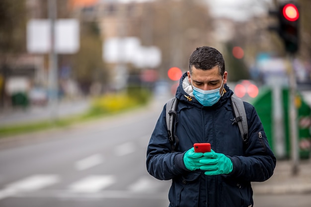 Worried man with mask checking phone on street