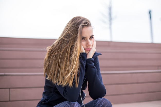 Worried, sad and depressing young woman sits outside