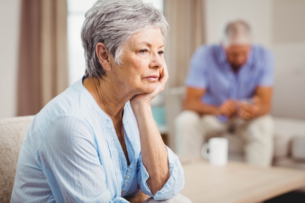 Worried senior woman sitting on sofa in living room