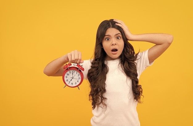 Worried teen girl hold retro alarm clock showing time late awakening