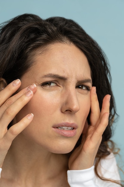 Worried woman has signs of aging skin, checking crows feet troubled with wrinkles on face