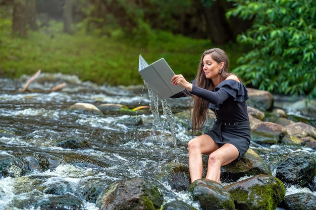 Worried woman pulls out of water laptop that fell into river remote holiday work accident