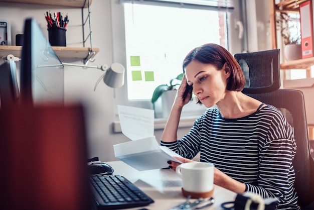 Worried Woman reading mail at the office