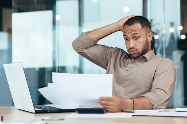 Worried young african american male student holding papers in hands i received a letter bad exam