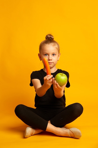 Wow its organic surprised little girl yellow background small child holds organic apple and carrots eating natural organic food organic decision school health