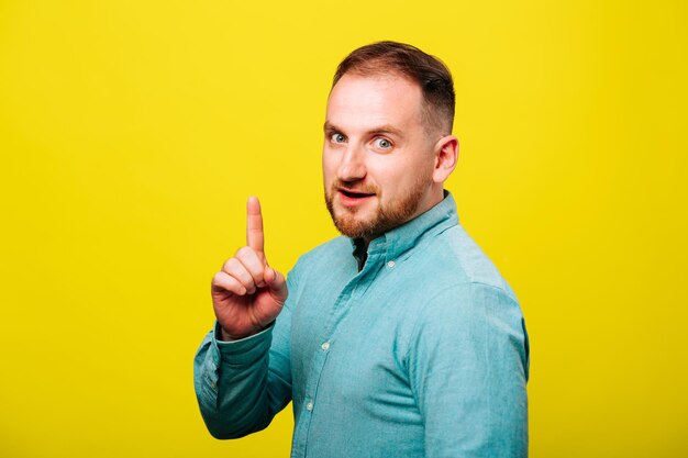 Wow look advertise here portrait of satisfied cute nice man with blue shirt pointing to empty place ...