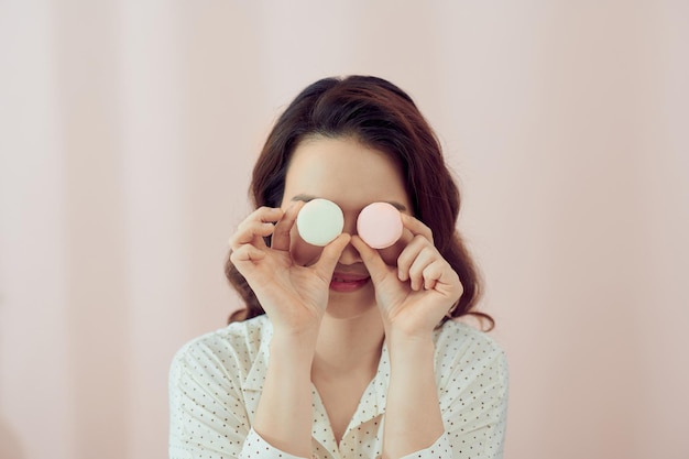 Wow young girl with macaron on pastel pink background