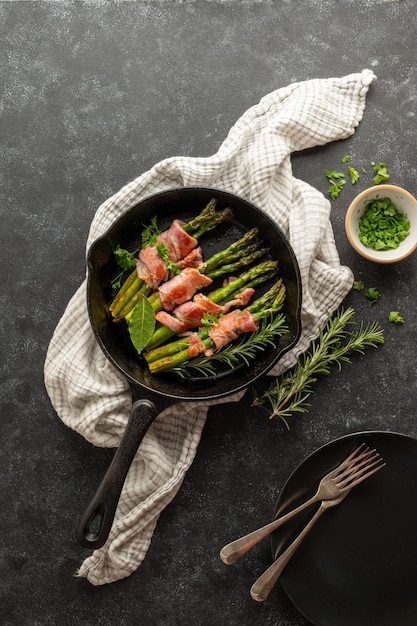 Wrapped asparagus with bacon in frying pan Dark background