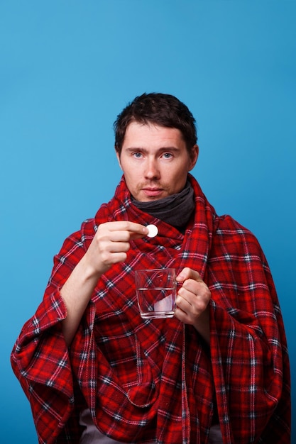 A wrapped in a blanket sick man with tablet and mug