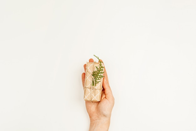 Wrapped Christmas gift in woman hands above white background