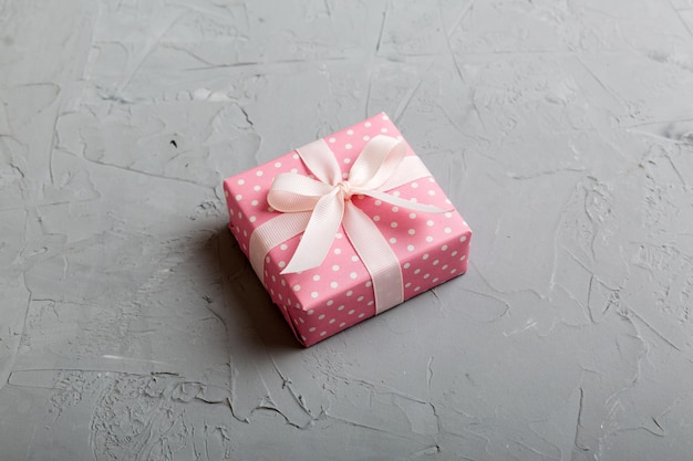 Wrapped Christmas or other holiday handmade gift box in color paper with ribbon on colored background Present box decoration of gift on colored table top view with copy space