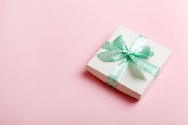 Wrapped Christmas or other holiday handmade present in white paper with green ribbon on colored background Present box decoration of gift on colored table top view with copy space