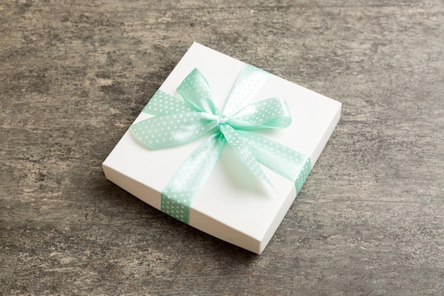 Wrapped Christmas or other holiday handmade present in white paper with green ribbon on colored background Present box decoration of gift on colored table top view with copy space