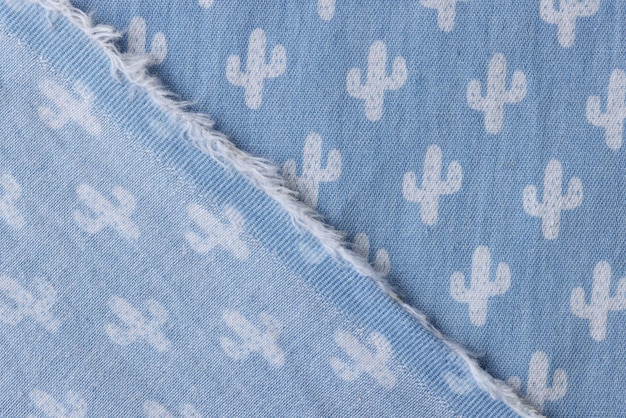 Wrapped corner of blue denim fabric with white cactus pattern designed for kids clothes smooth