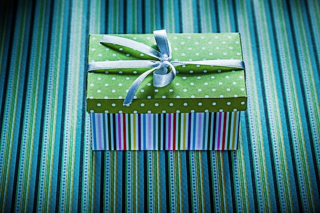 Wrapped gift box on striped background holidays concept