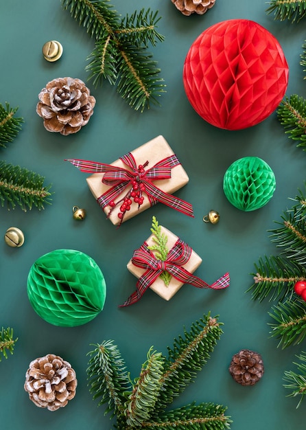 Wrapped gift boxes between Christmas decorations and green fir branches on green