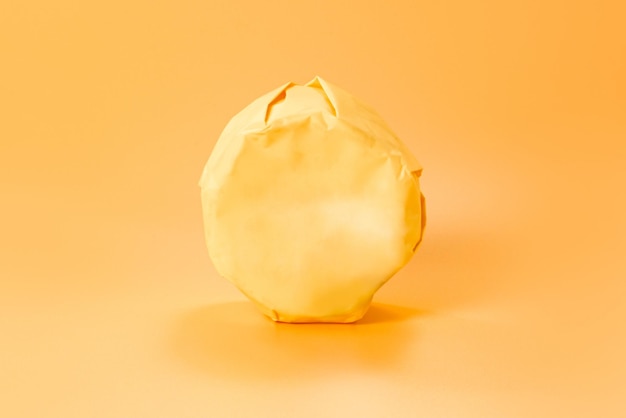 Wrapped unopened paper package of a whole head of camembert on an orange background Soft Dairy Meal Object Fat