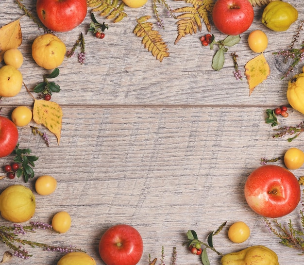 Wreath made of autumn leaves berries apples and nuts on wooden background Autumn concept