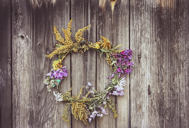 Wreath of wild flowers on the old wooden door background. Authentic decor.