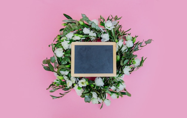 Wreath with white roses on pink background. Decorated. Above view