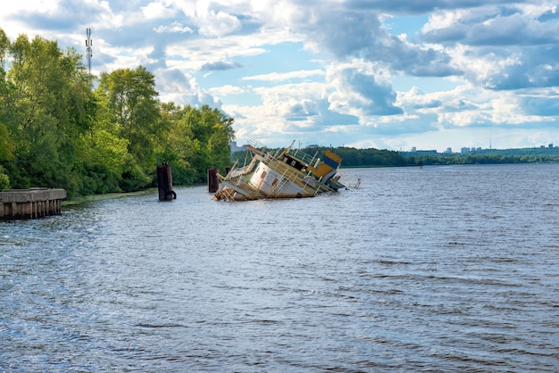 Wreck of abandoned sink ship near river coast