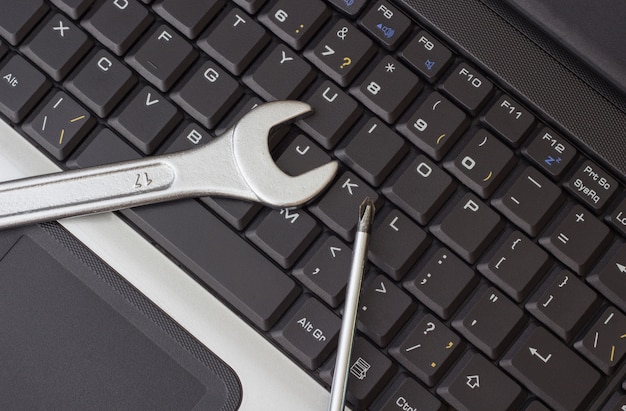 Photo a wrench and a screwdriver on the laptop keyboard