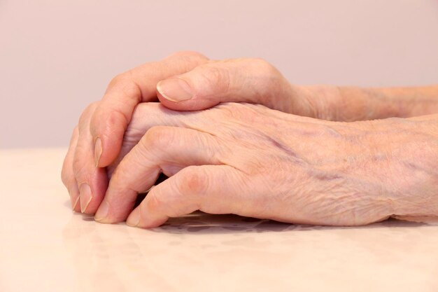 Photo wrinkled grandmother's hands folded on a white background