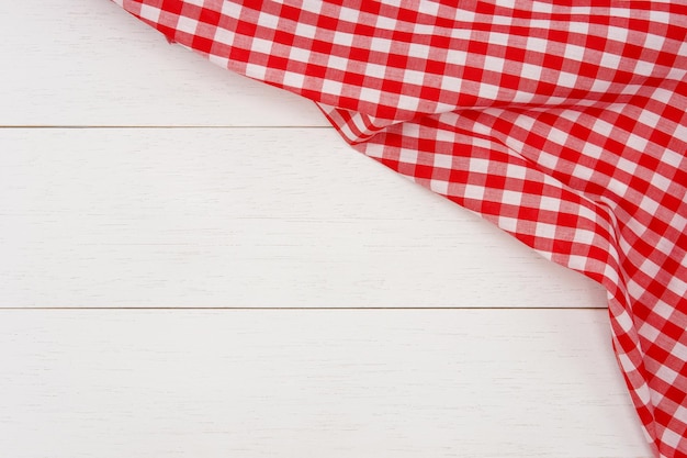 Wrinkled red gingham fabric on rustic white wood plank background with copy space