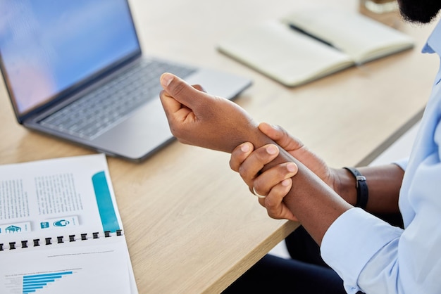 Wrist pain business man and muscle injury while sitting at desk and working as a data analyst Closeup hand of a black male entrepreneur suffering from carpal tunnel syndrome or arthritis in office