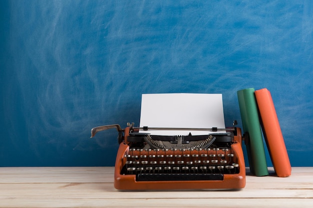 Writer's workplace red typewriter and books on blue blackboard background