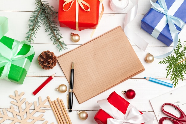 Writing christmas greeting cards. Open notepad with pen on decorated wooden table