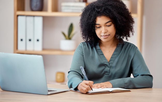 Writing notebook and laptop with a business woman at work on her schedule at her desk in the office Computer pen and planning with a female designer or employee working on planning in her startup