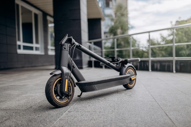 XAFolded Electric scooter on concrete surface on urban street near modern building