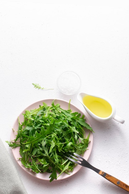 XAFresh arugula leaves with oil and salt in a plate on a white background top view