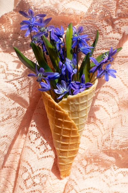 XASpring blue flowers in a waffle cone on a textile background with sunlight