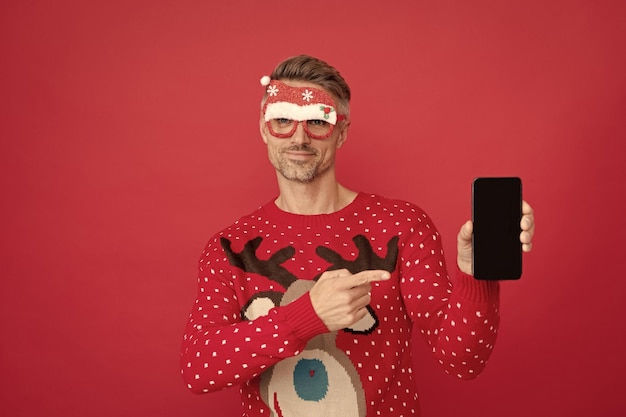 Xmas guy point finger on phone screen on red background happy new year