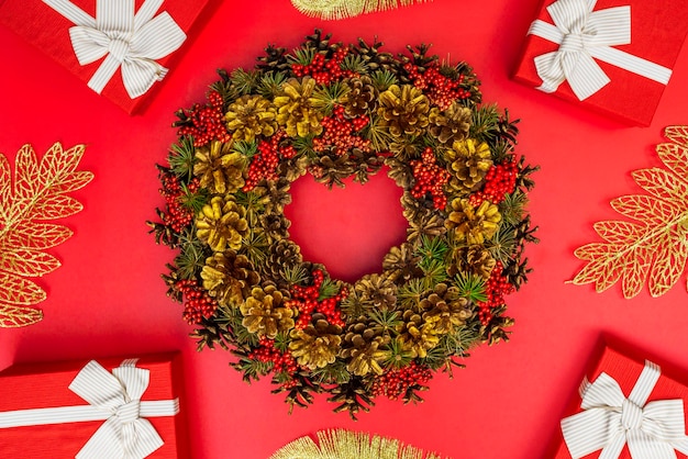 Xmas wreath and gift boxes with white ribbon on red background New Year background Flat lay top view