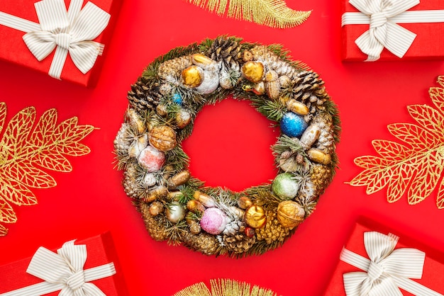 Xmas wreath and gift boxes with white ribbon on red background New Year background Flat lay top view