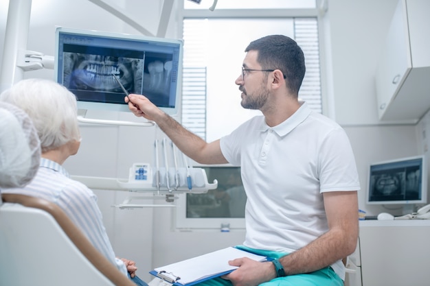 Xray results. Male young dentist explaining the results of xray to his female patient