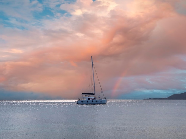 Yacht-catamaran on a cloudy day on the calm Aegean Sea on island of Evia, Greece at sunset