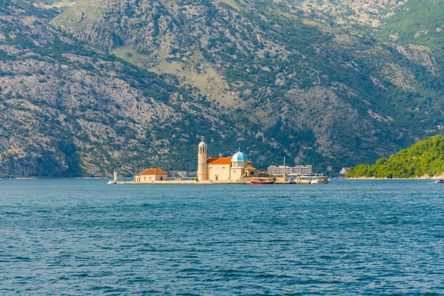 The yacht sails near the picturesque Gospa od Skrpela Island in the Boka Kotorsky Bay